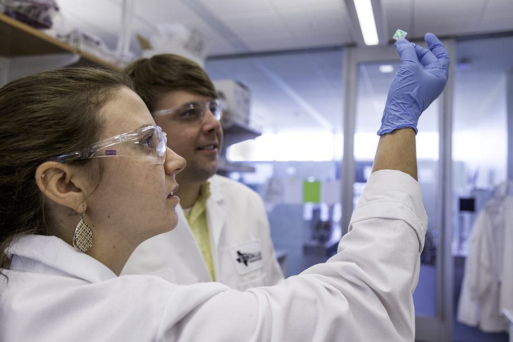 Graduate Student analyzes at graduated cylinders and beakers.