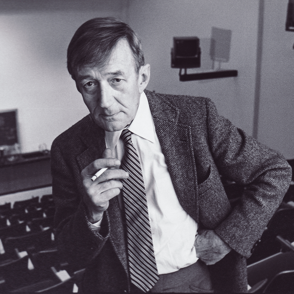 Dr. Kusch sits in a classroom and holds a cigarette.