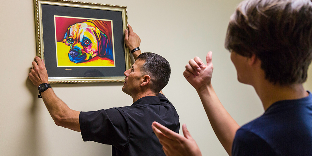 Austin Whittle and his dad team up to hang a colorful portrait of a dog that closely resembles their family dog, Whiskey.