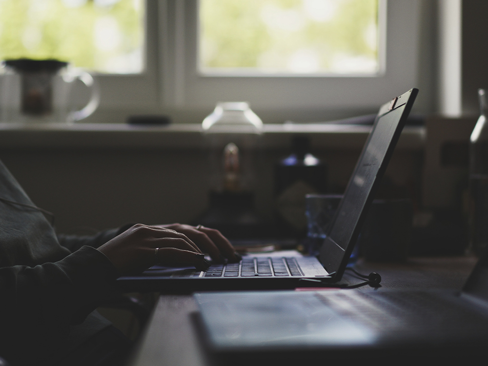 A person works on a laptop at their home