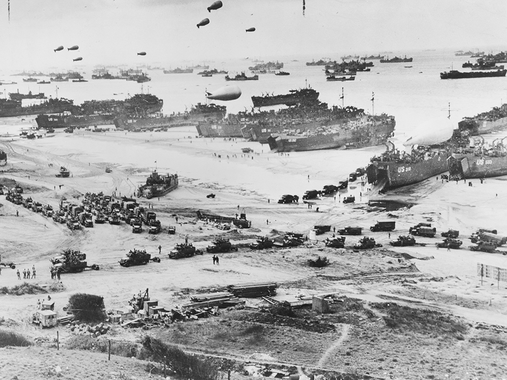 Bird's-eye view of landing craft, barrage balloons, and allied troops landing in Normandy, France on D-Day